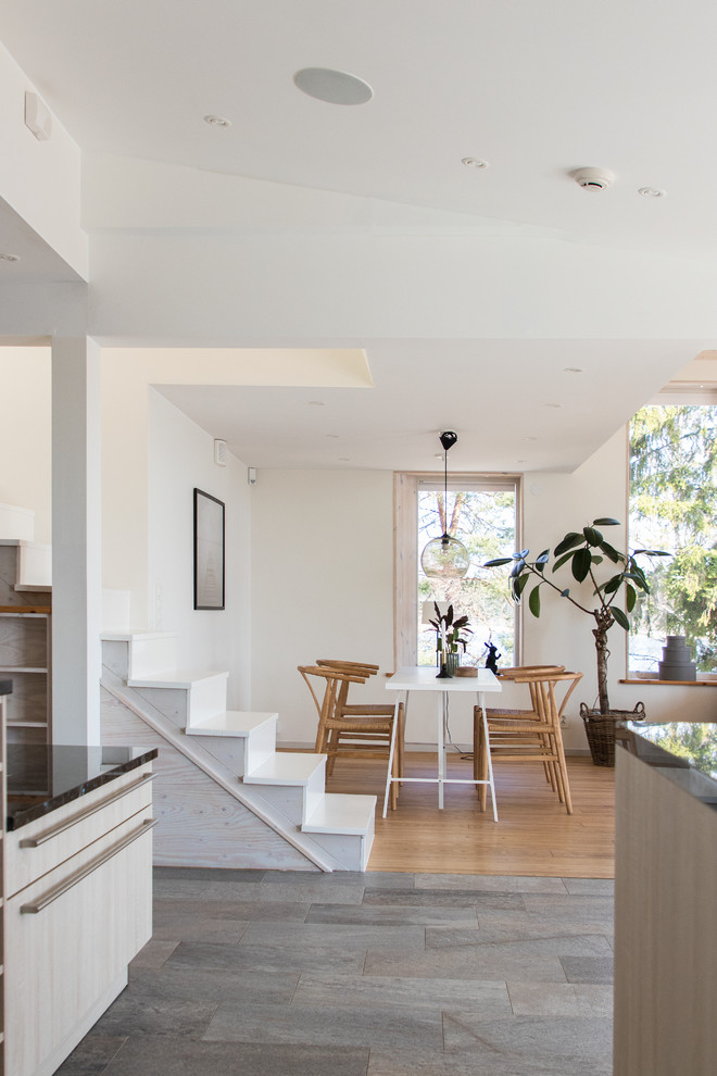 Idéer för att renovera en mellanstor minimalistisk matplats med öppen planlösning, med vita väggar, kalkstensgolv och grått golv