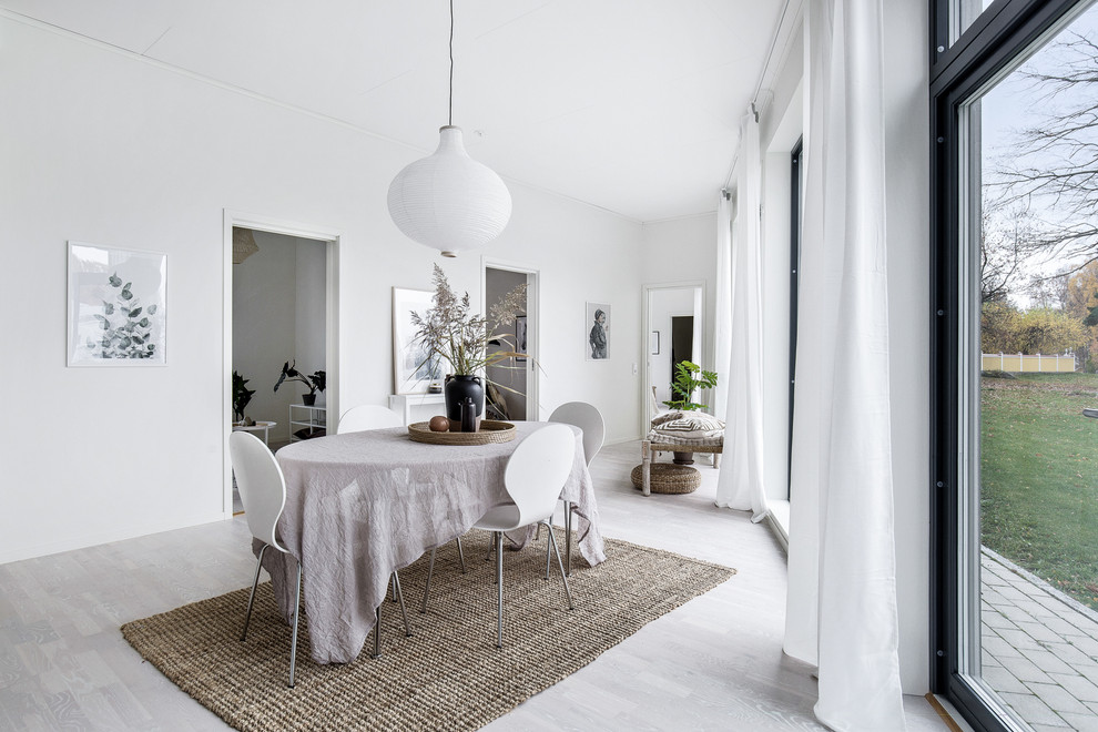 Photo of a scandinavian dining room in Other with white walls, light hardwood flooring and grey floors.