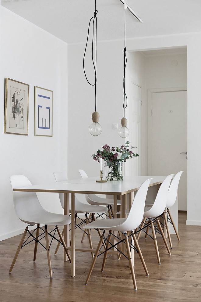 Cette image montre une salle à manger nordique de taille moyenne avec un mur blanc, un sol en bois brun et un sol marron.