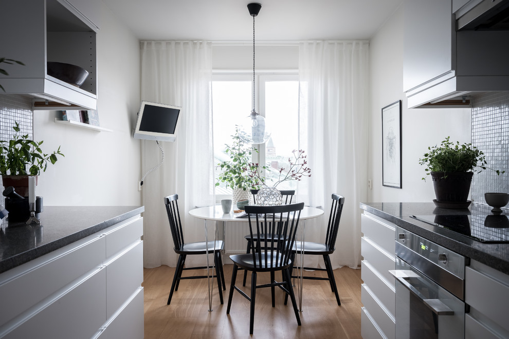 Idéer för minimalistiska matplatser, med vita väggar, mellanmörkt trägolv och beiget golv