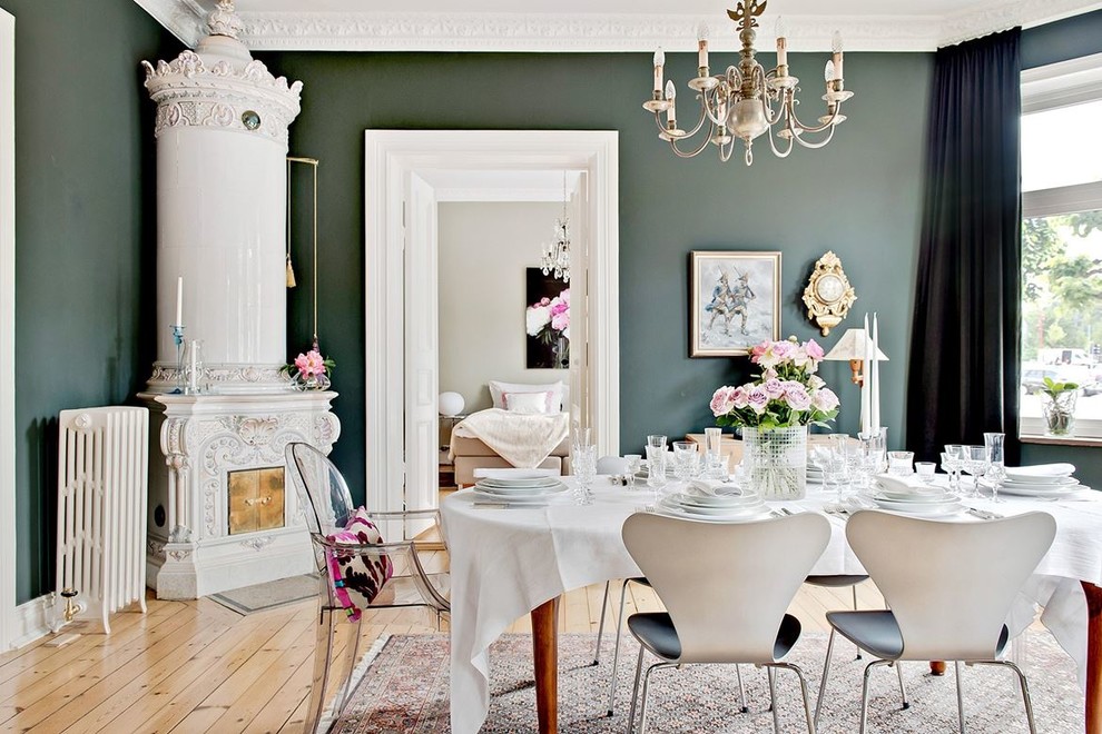 На фото: столовая в скандинавском стиле с зелеными стенами, светлым паркетным полом, угловым камином и бежевым полом