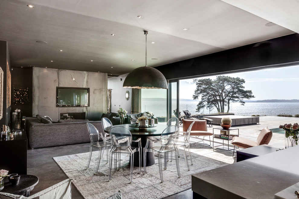 Immagine di una grande sala da pranzo aperta verso il soggiorno minimal con pareti grigie, pavimento in cemento e pavimento grigio