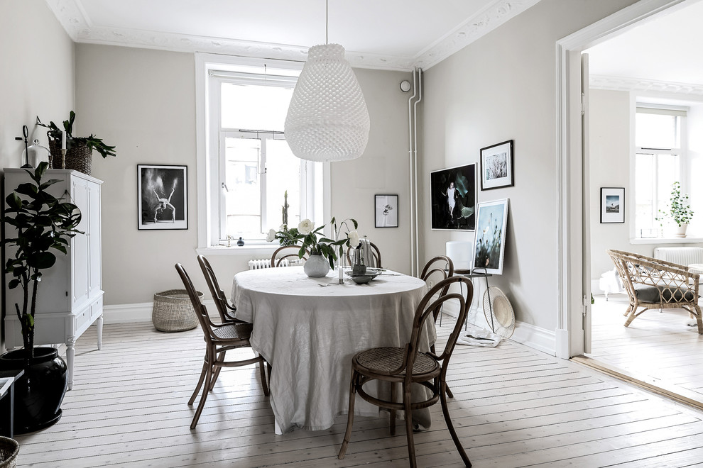Immagine di una grande sala da pranzo scandinava con pareti bianche, parquet chiaro e pavimento beige