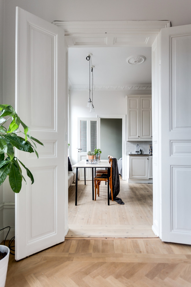 Photo of a victorian kitchen/dining room in Stockholm with white walls and light hardwood flooring.