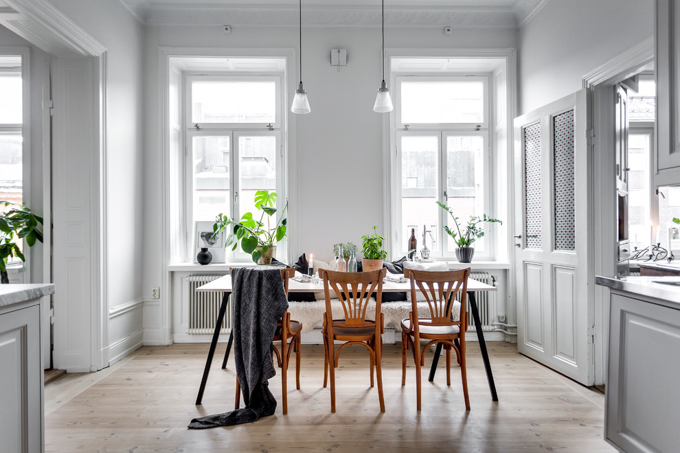 Mid-sized danish light wood floor kitchen/dining room combo photo in Stockholm with white walls