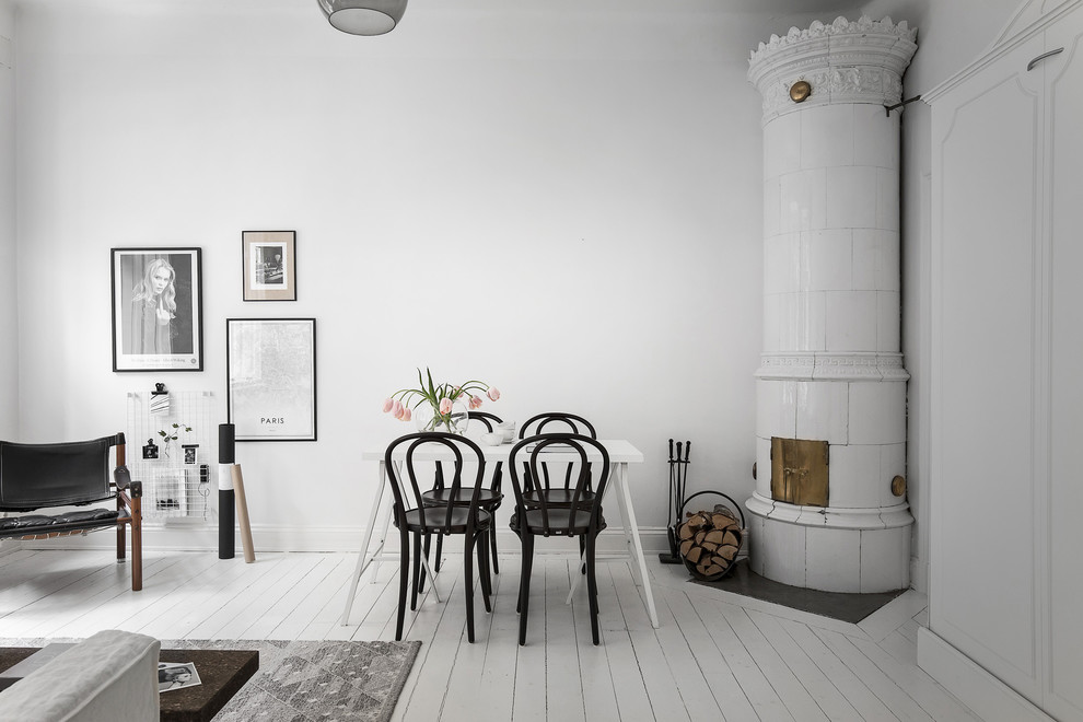Offenes, Mittelgroßes Skandinavisches Esszimmer mit weißer Wandfarbe, gebeiztem Holzboden, Kaminofen, gefliester Kaminumrandung und weißem Boden in Stockholm