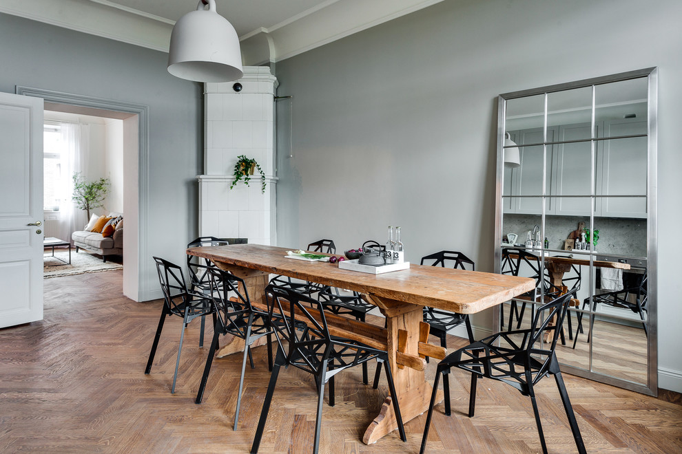 Cette photo montre une grande salle à manger scandinave avec un mur gris, un sol en bois brun et aucune cheminée.