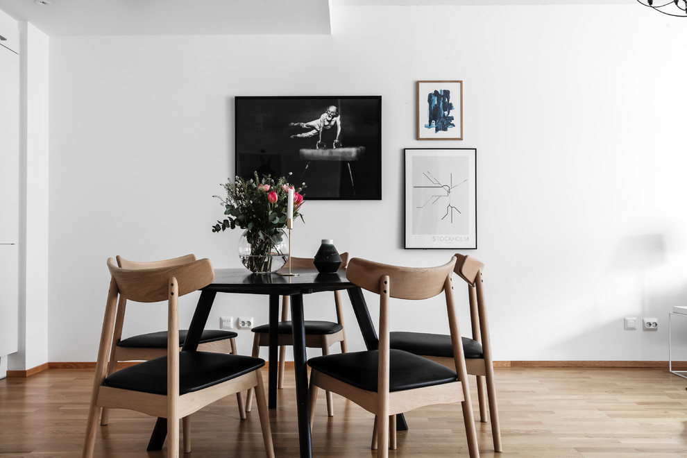 Photo of a small scandinavian dining room in Stockholm with white walls, light hardwood flooring and beige floors.