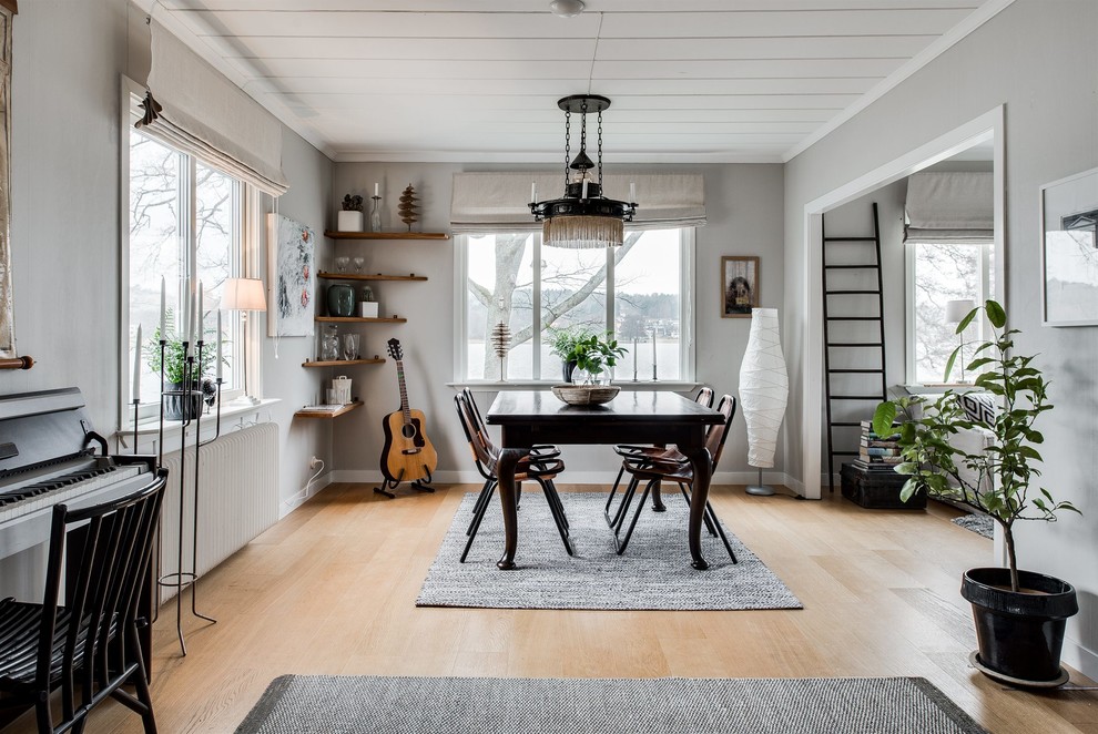 Immagine di una sala da pranzo aperta verso il soggiorno scandinava di medie dimensioni con pareti bianche, pavimento in legno massello medio e nessun camino