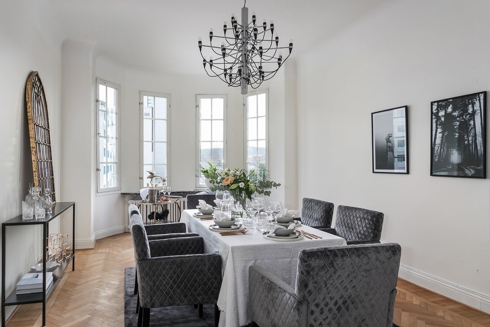 Scandinavian dining room in Gothenburg with white walls, medium hardwood flooring and beige floors.
