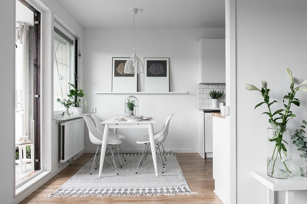 Foto på en mellanstor minimalistisk matplats, med vita väggar och mellanmörkt trägolv