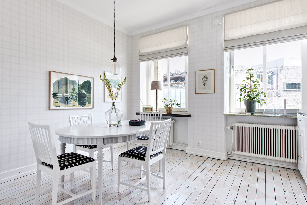 На фото: столовая в скандинавском стиле с белыми стенами, деревянным полом и белым полом