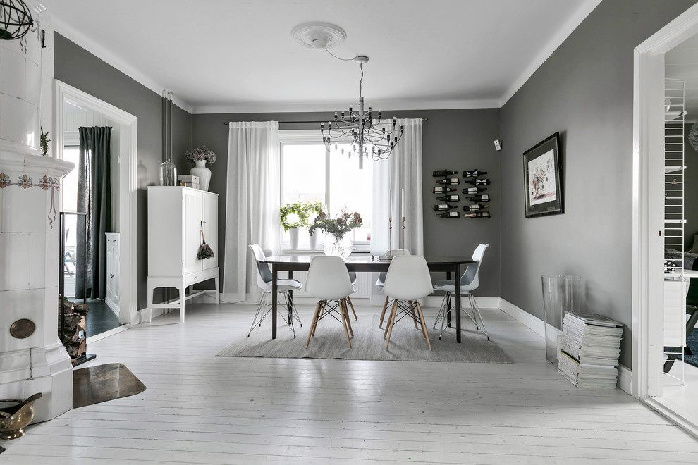 Inspiration pour une salle à manger nordique fermée et de taille moyenne avec un mur gris, parquet peint, un sol blanc et une cheminée d'angle.