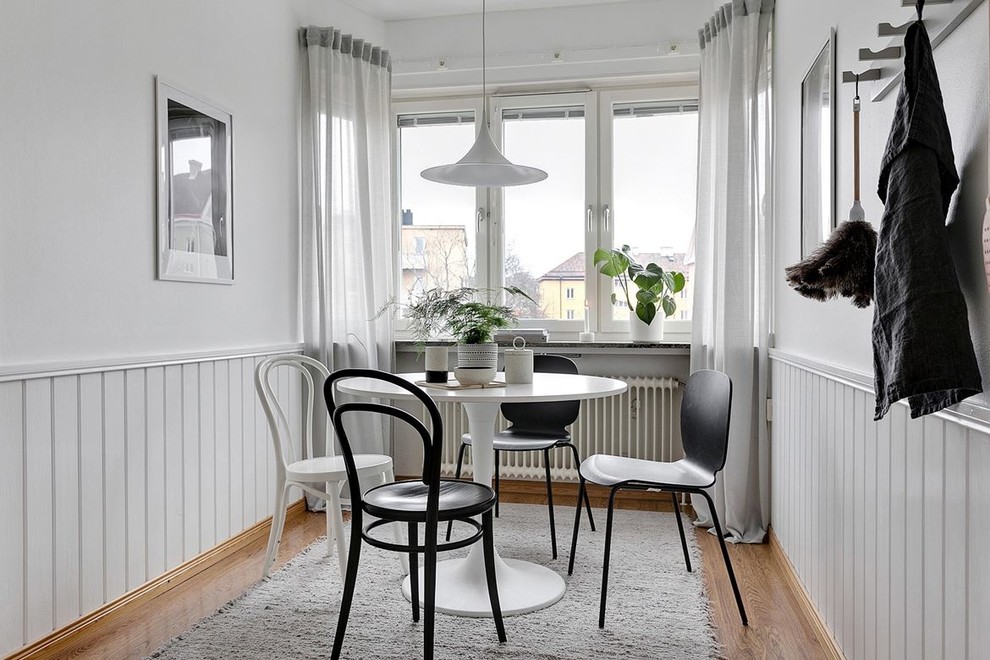 Photo of a small scandinavian dining room in Stockholm with white walls, medium hardwood flooring and beige floors.