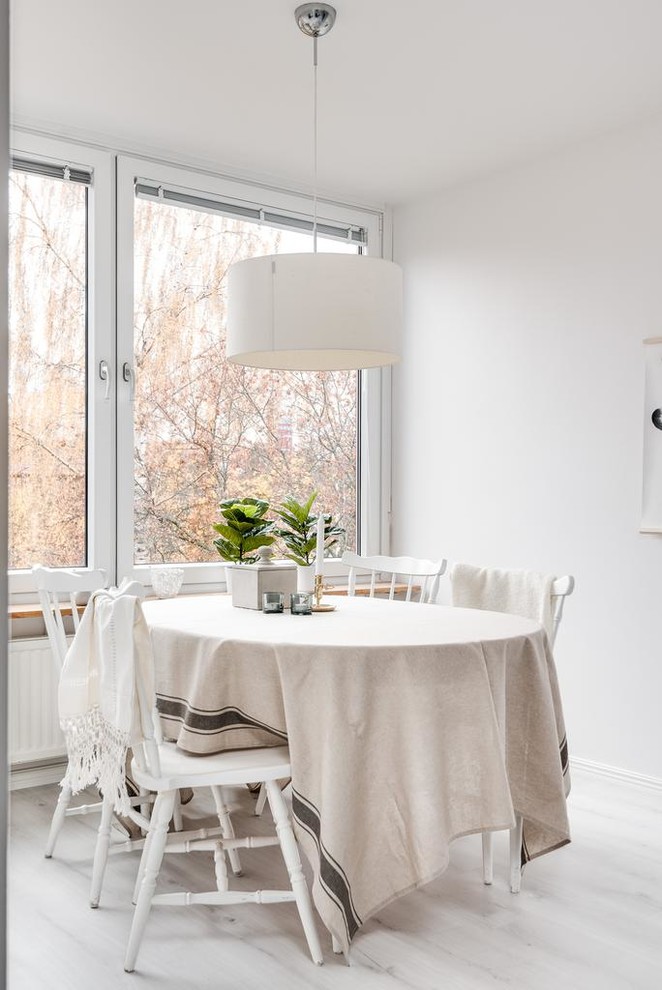 На фото: столовая в скандинавском стиле с белыми стенами, светлым паркетным полом и белым полом
