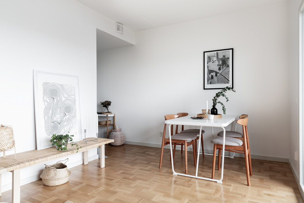 Esempio di una sala da pranzo aperta verso la cucina scandinava di medie dimensioni con pareti bianche, parquet chiaro e pavimento beige