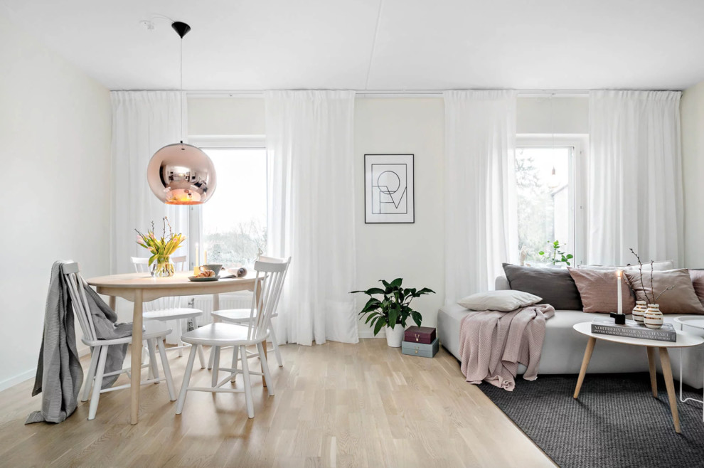 This is an example of a medium sized scandinavian open plan dining room in Stockholm with white walls, light hardwood flooring and beige floors.