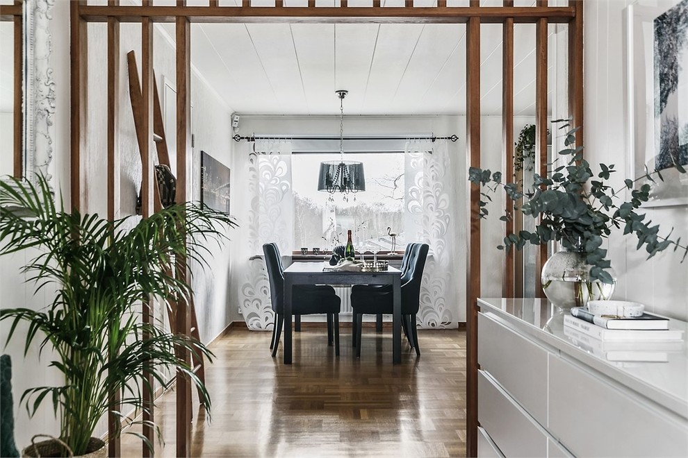 Idée de décoration pour une salle à manger nordique fermée avec un mur blanc, un sol en bois brun, aucune cheminée et un sol marron.