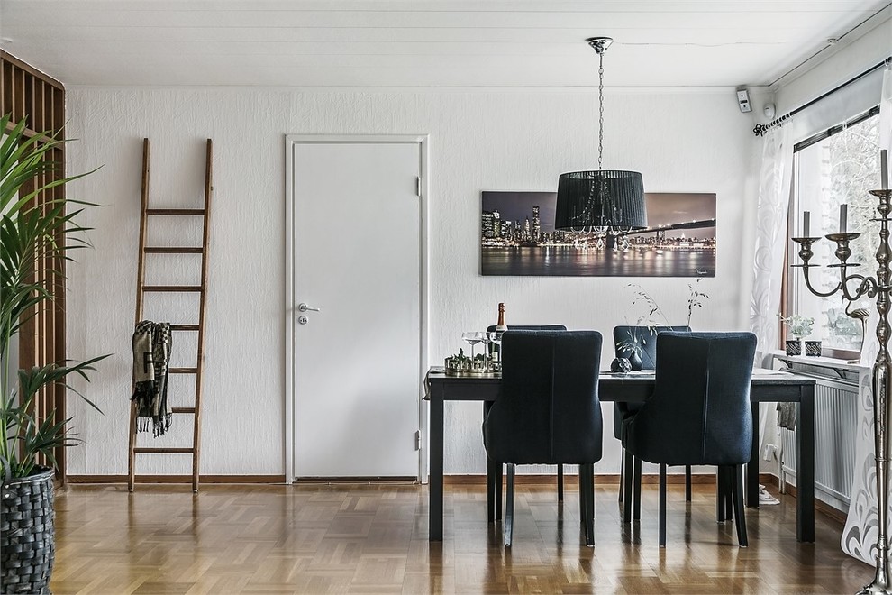 Imagen de comedor nórdico con paredes blancas, suelo de madera en tonos medios y suelo marrón