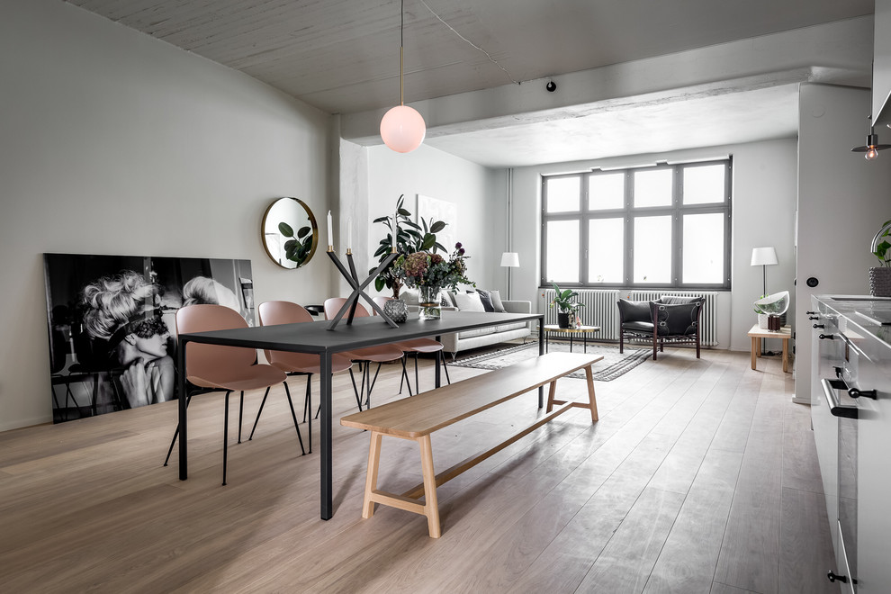 This is an example of a scandi open plan dining room in Stockholm with white walls, light hardwood flooring and beige floors.