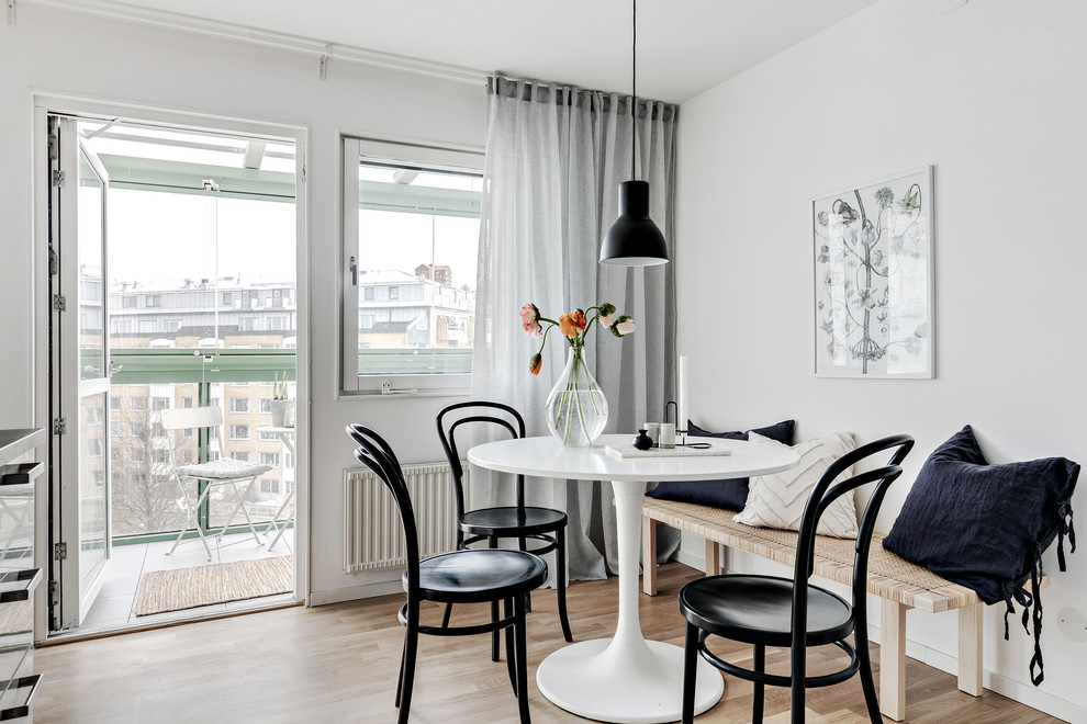 Small scandi dining room in Gothenburg with white walls, beige floors and light hardwood flooring.