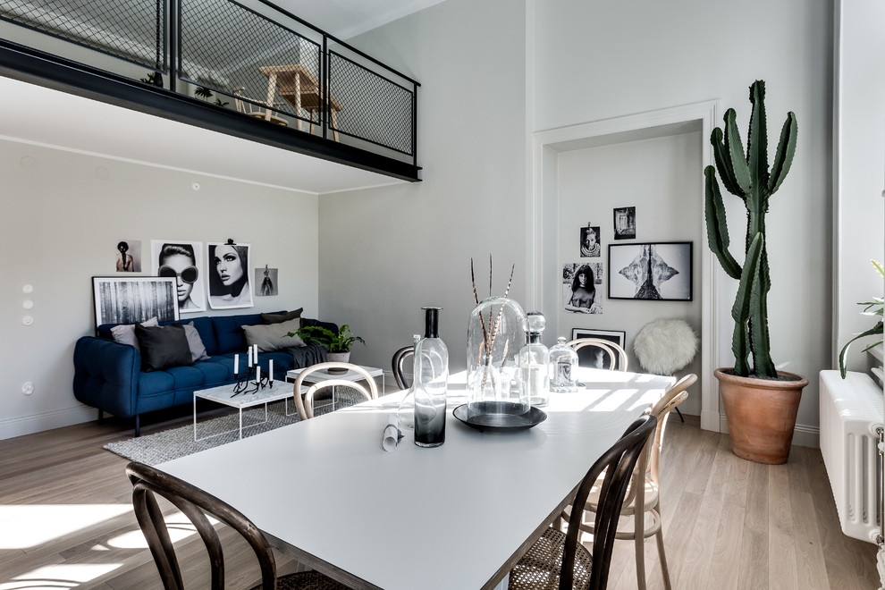 Aménagement d'une grande salle à manger ouverte sur le salon scandinave avec un mur blanc et parquet clair.