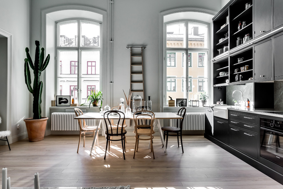 Imagen de comedor escandinavo grande abierto con suelo de madera en tonos medios y paredes grises