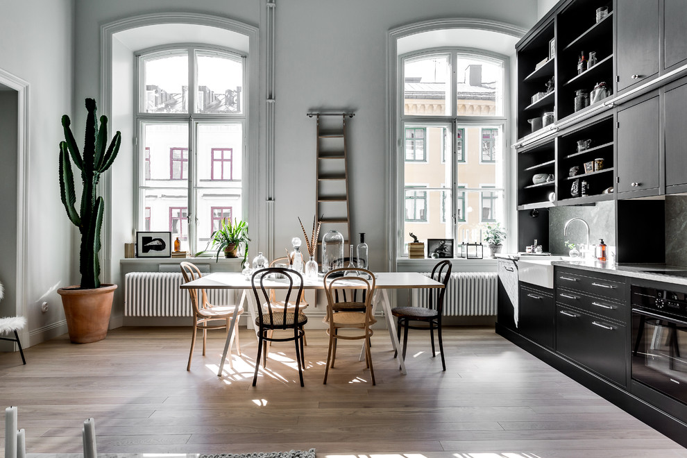 Idée de décoration pour une grande salle à manger ouverte sur le salon nordique avec un sol en bois brun et un mur gris.