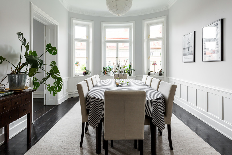 Esempio di una sala da pranzo scandinava chiusa e di medie dimensioni con pareti bianche, pavimento in legno verniciato, nessun camino e pavimento nero