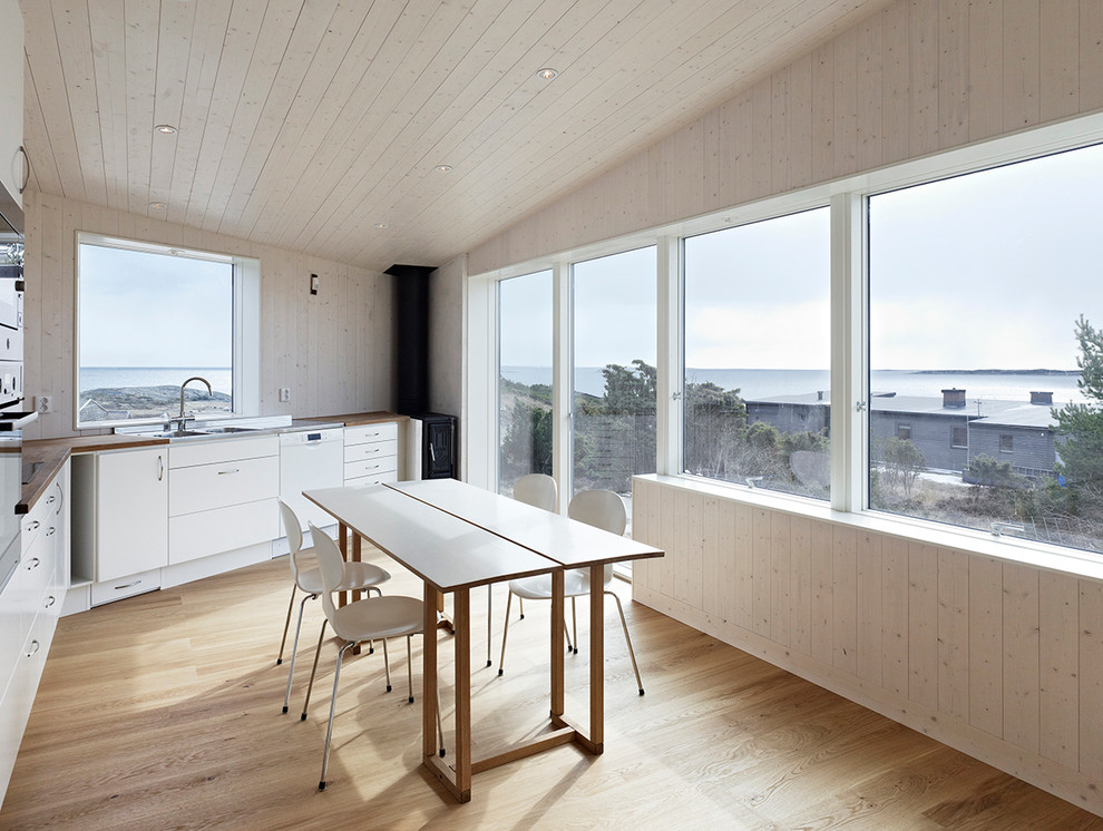 Cette image montre une petite salle à manger ouverte sur la cuisine design avec un mur blanc, parquet clair et aucune cheminée.