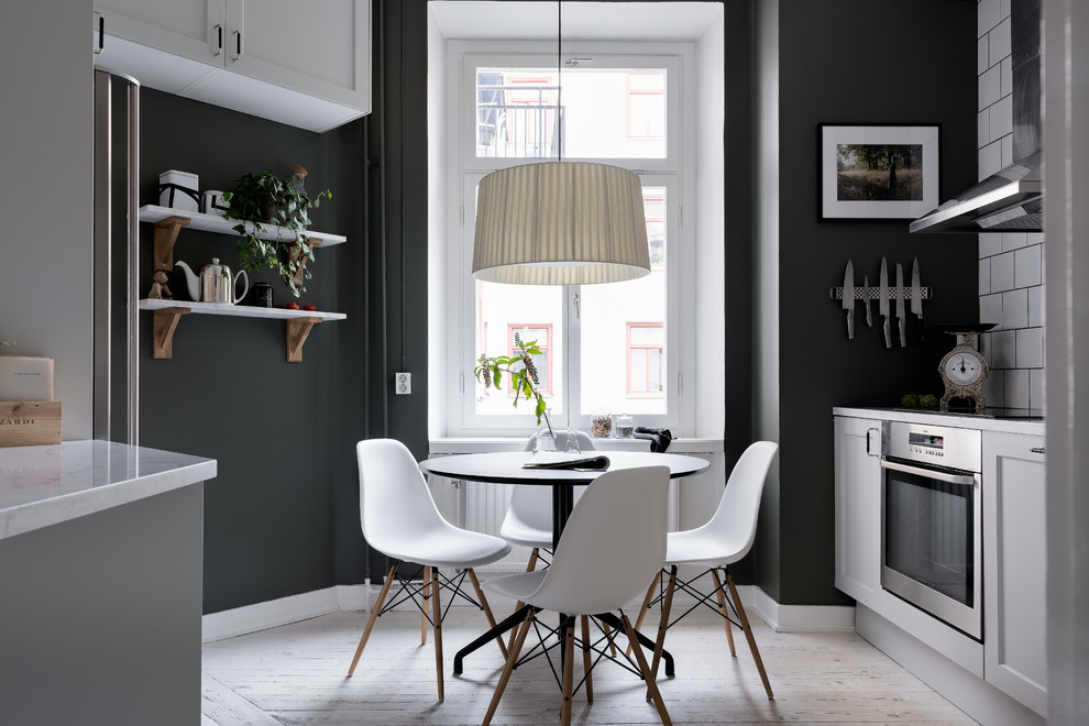 Esempio di una sala da pranzo aperta verso la cucina nordica di medie dimensioni con pareti nere, parquet chiaro e pavimento beige