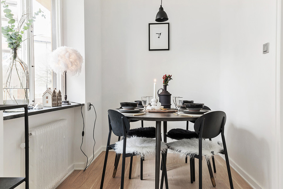 На фото: столовая среднего размера в скандинавском стиле с белыми стенами и светлым паркетным полом без камина с