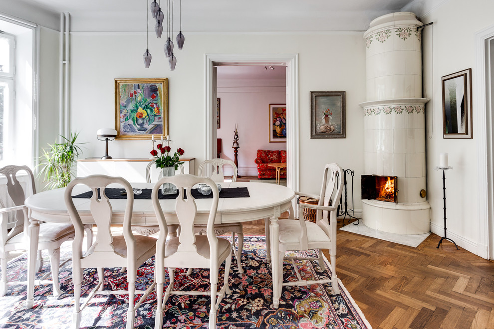 Свежая идея для дизайна: отдельная столовая в скандинавском стиле с белыми стенами, паркетным полом среднего тона, угловым камином и коричневым полом - отличное фото интерьера