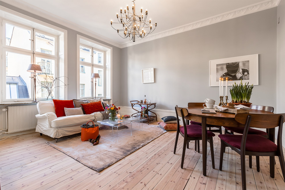 Immagine di una sala da pranzo aperta verso il soggiorno scandinava di medie dimensioni con pareti grigie, parquet chiaro e nessun camino
