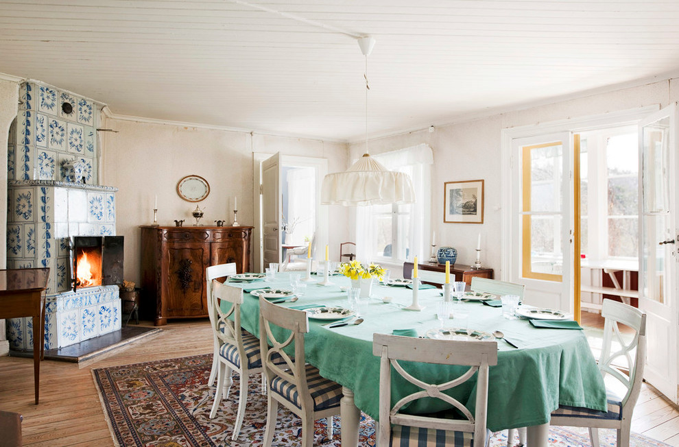 Photo of a large country kitchen/dining room in Stockholm with beige walls, medium hardwood flooring and a corner fireplace.