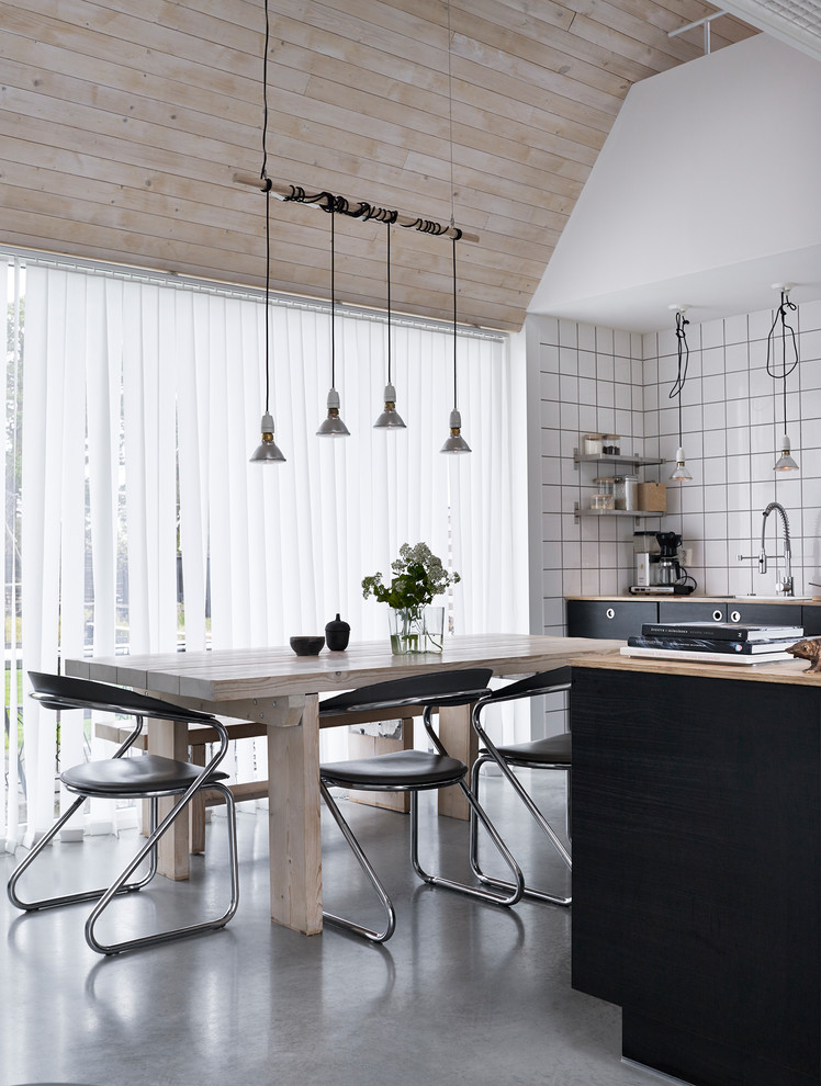 Foto di una sala da pranzo aperta verso la cucina industriale con pareti bianche, pavimento in cemento e pavimento grigio