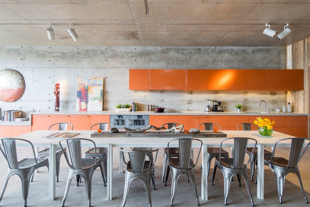 Réalisation d'une salle à manger ouverte sur la cuisine bohème avec un mur gris, sol en béton ciré et aucune cheminée.