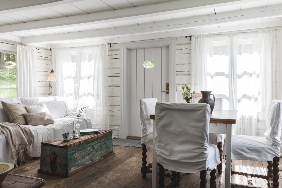 Foto di una sala da pranzo aperta verso il soggiorno stile shabby con pareti bianche, parquet scuro e pavimento marrone
