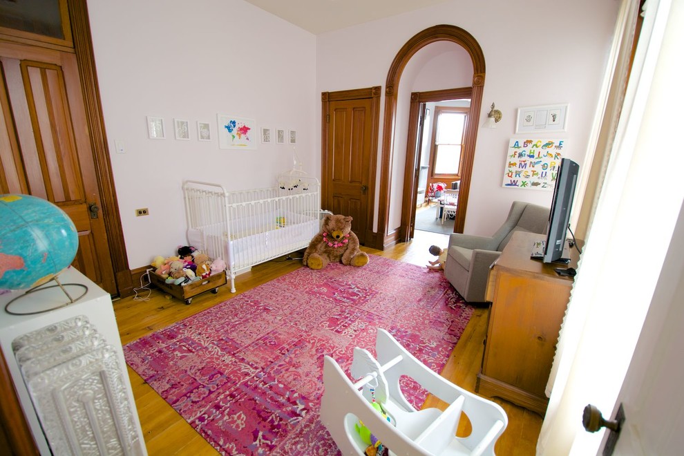 Design ideas for a medium sized victorian nursery for girls in Other with pink walls, light hardwood flooring and brown floors.