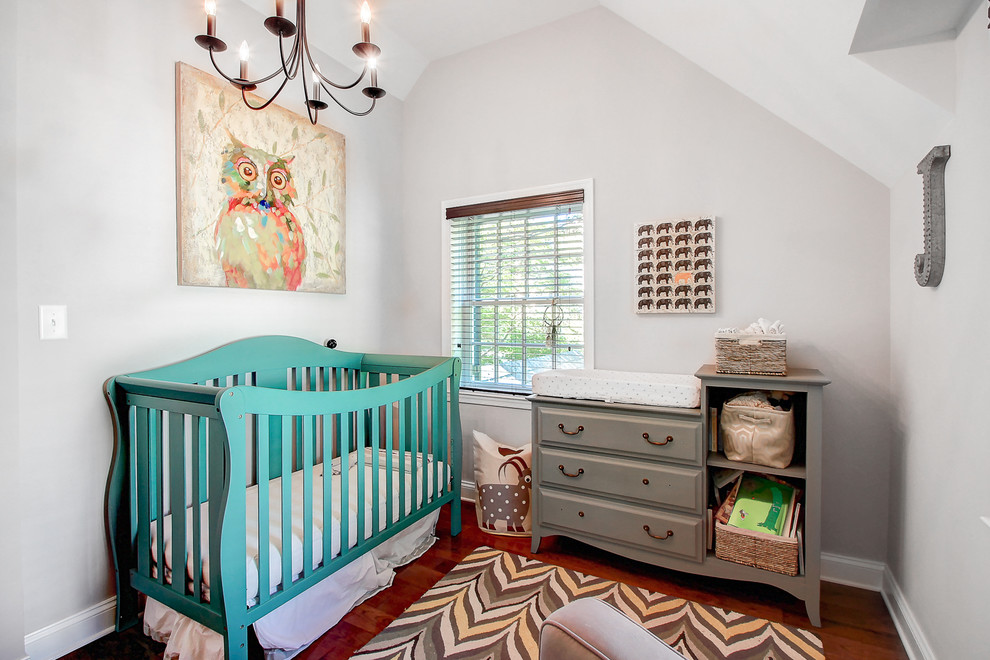 Diseño de habitación de bebé neutra clásica renovada pequeña con paredes grises y suelo de madera en tonos medios
