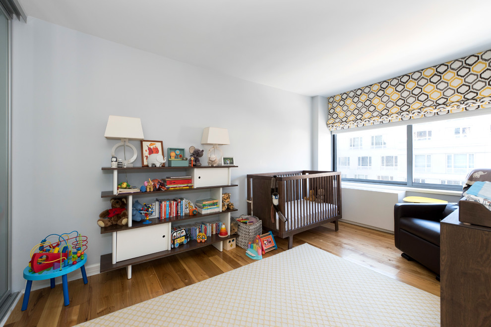Ejemplo de habitación de bebé neutra minimalista de tamaño medio con paredes grises y suelo de madera clara