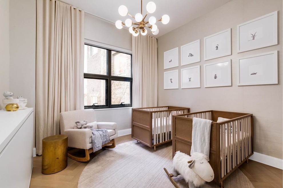 Photo of a traditional gender neutral nursery in New York with beige walls, medium hardwood flooring, brown floors and feature lighting.