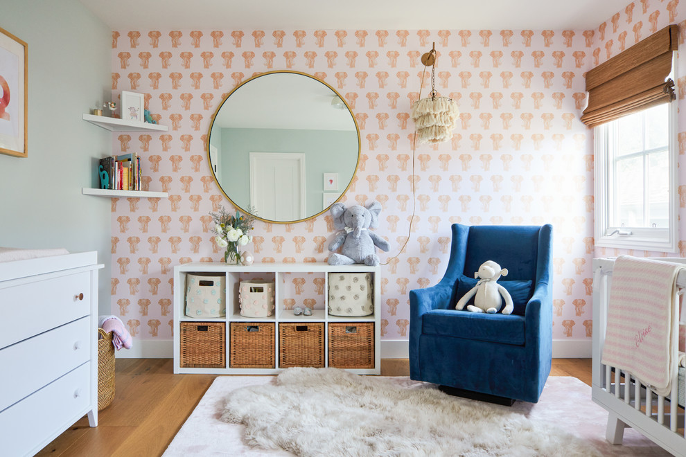 Inspiration for a coastal nursery for girls in Los Angeles with pink walls, light hardwood flooring and feature lighting.