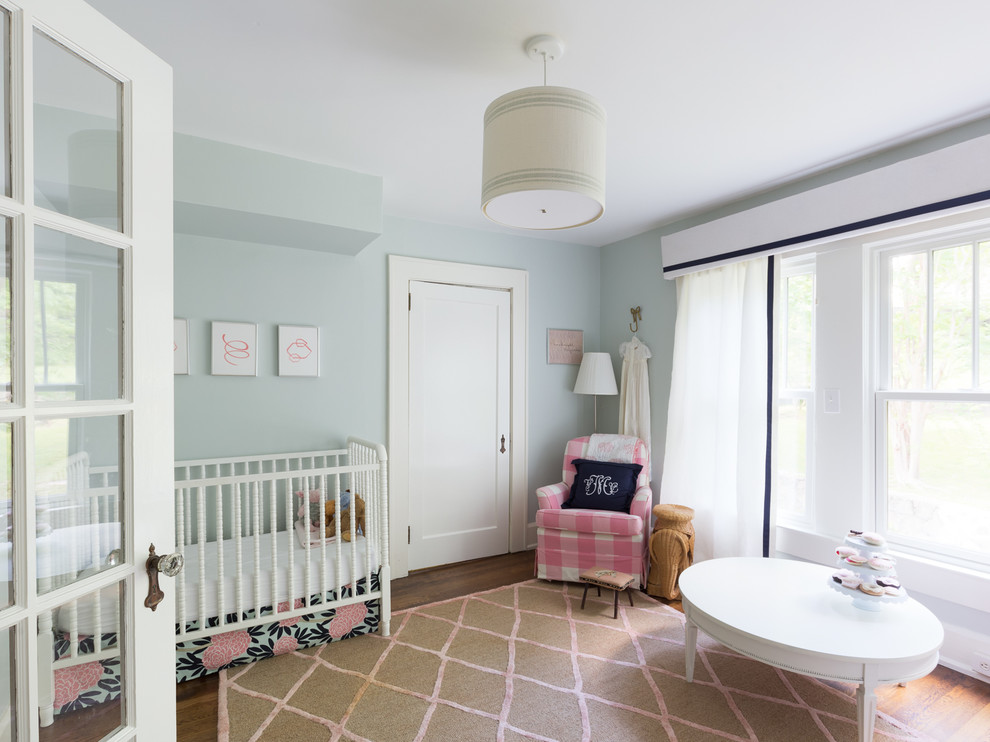 Idee per una cameretta per neonata tradizionale di medie dimensioni con pareti blu e pavimento in legno massello medio