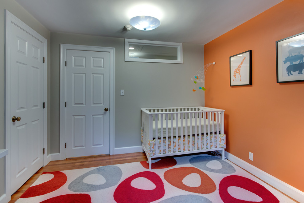 На фото: нейтральная комната для малыша в стиле неоклассика (современная классика) с оранжевыми стенами и паркетным полом среднего тона с