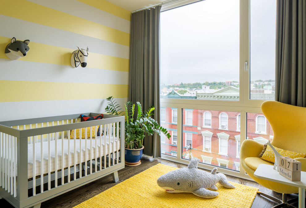 Cette photo montre une chambre de bébé neutre tendance avec un mur jaune, parquet foncé et un sol marron.