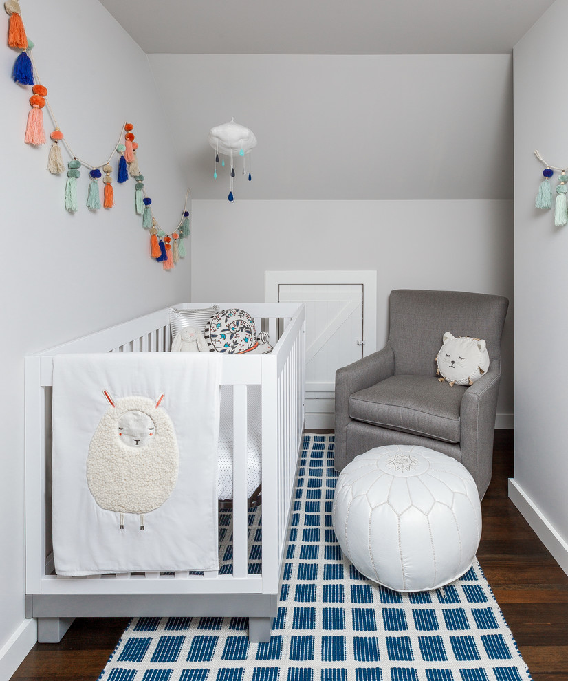 Diseño de habitación de bebé neutra clásica renovada pequeña con paredes grises, suelo de madera en tonos medios y suelo marrón