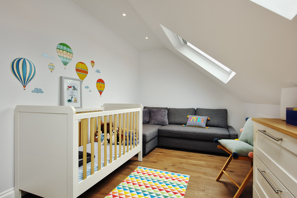 Ejemplo de habitación de bebé neutra nórdica con paredes blancas y suelo de madera en tonos medios