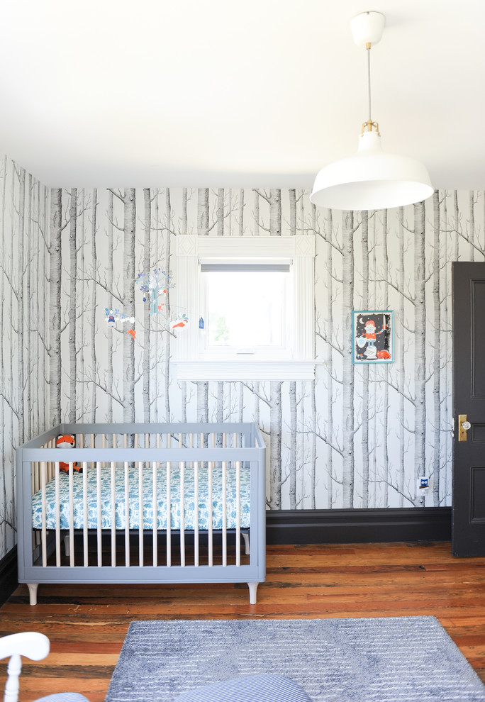 Cette image montre une chambre de bébé neutre bohème de taille moyenne avec un mur blanc et un sol en bois brun.