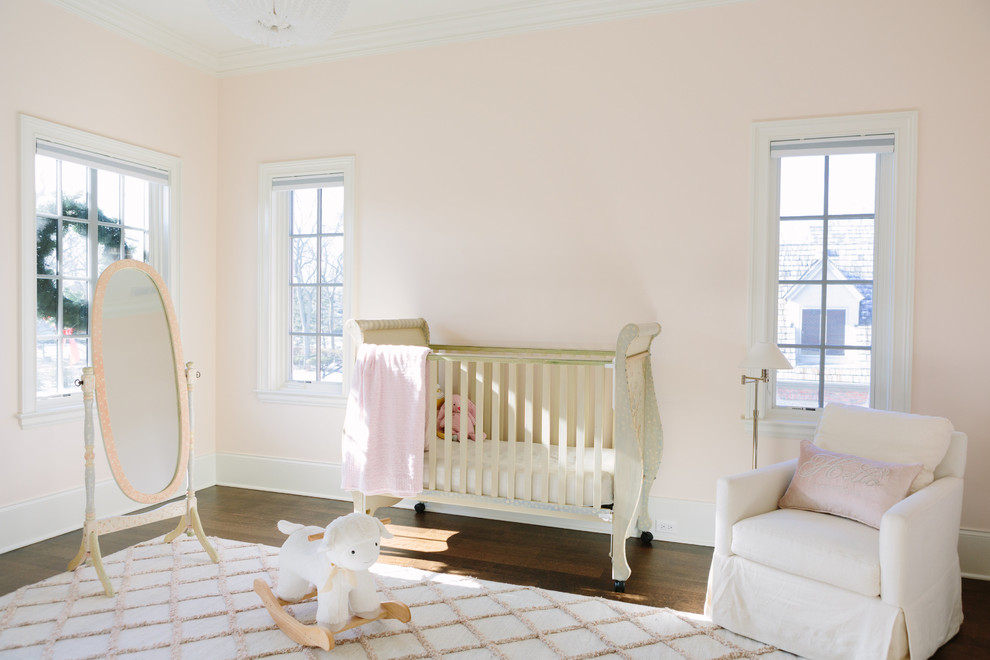 Idée de décoration pour une chambre de bébé fille tradition avec un mur rose, parquet foncé et un sol marron.